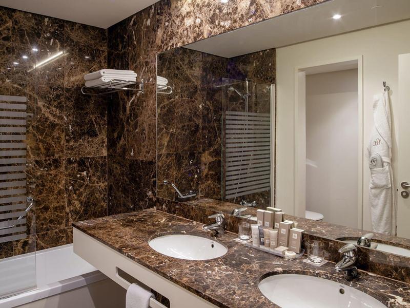 Bagno di lusso moderno in hotel con design in marmo marrone e doppio lavabo.