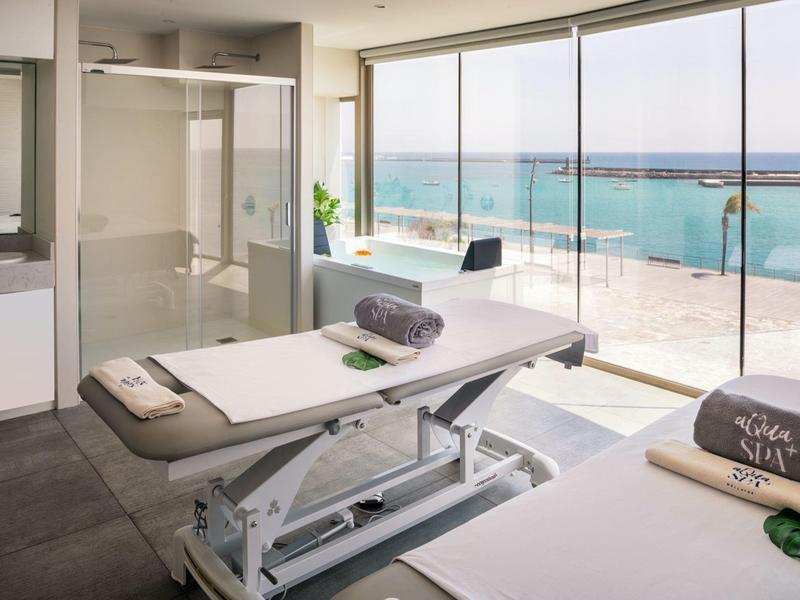 Camere per trattamenti spa luminose con letti, finestre panoramiche e vista sul mare.