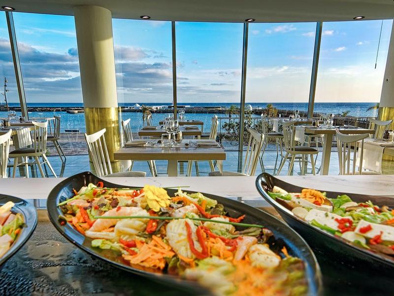Buffet con frutti di mare freschi davanti a una finestra panoramica con vista sul mare.