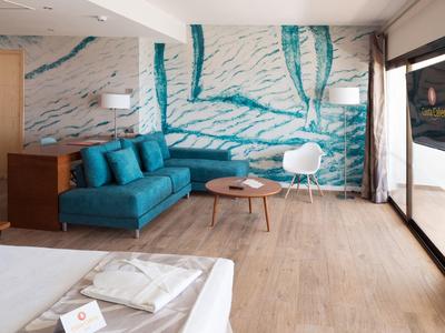 Modern eingerichtetes Wohnzimmer mit blauer Couch, Holzfußboden und großer Fensterfront.