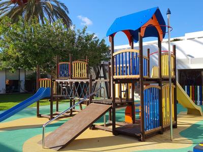 Bunter Kinderspielplatz mit Rutschen, Klettergerüst und weichem Bodenbelag unter blauem Himmel.