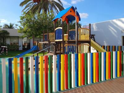 Bunter Spielplatz mit Holzklettergerüst, Rutsche und mehrfarbigem Staketenzaun.