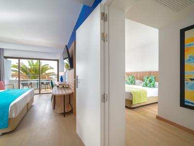 Modernes Hotelzimmer mit zwei Schlafzimmern, hellen Holzböden und Balkon mit Meeresblick.
