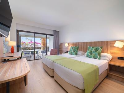 Modernes Hotelzimmer mit zwei Einzelbetten, Balkon und Blick auf den Pool.