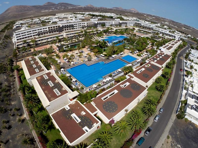 Grande complesso alberghiero con diverse piscine e edifici bianchi in un paesaggio arido.