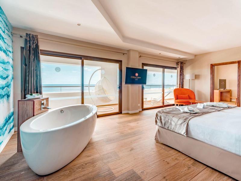 Camera d'hotel moderna con vasca indipendente e vista mare attraverso grandi finestre.