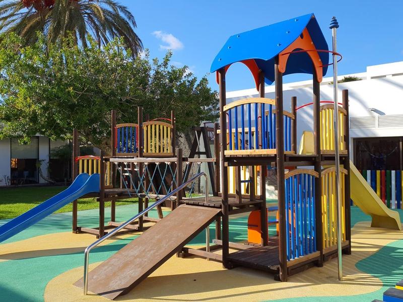 Area giochi colorata con scivoli e strutture da arrampicata sotto un cielo sereno.