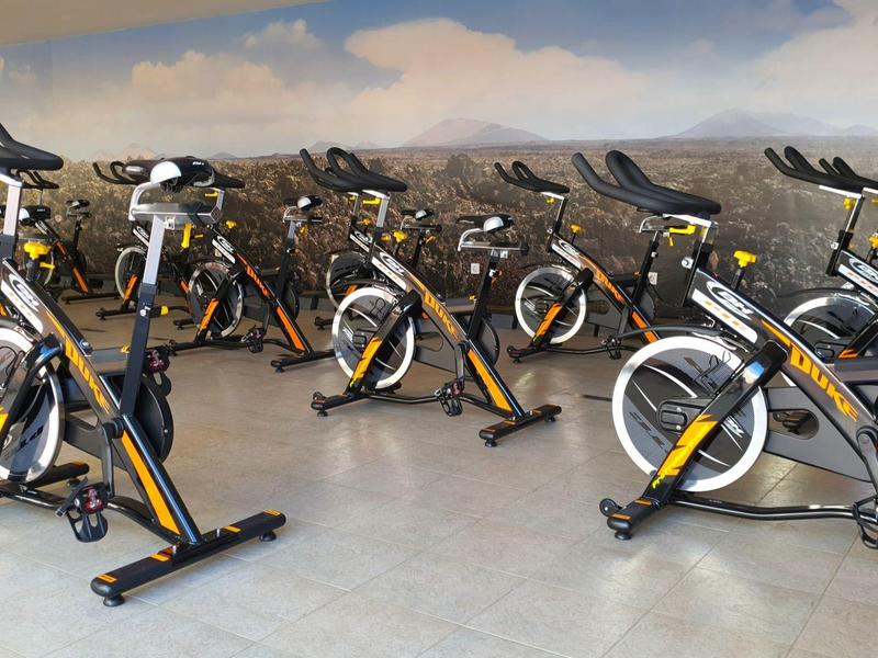 Diverse biciclette da palestra in una stanza con parete decorata con paesaggio.