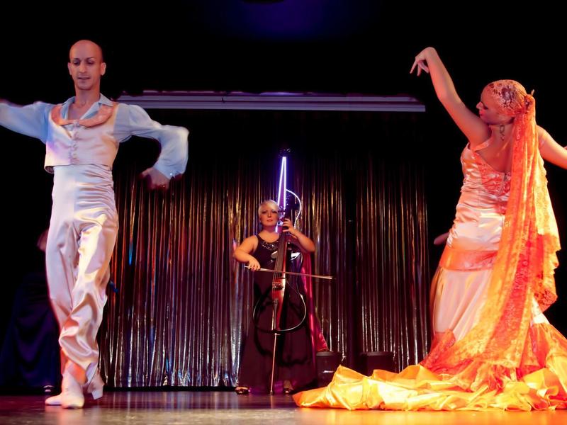 Due ballerini in abiti tradizionali con un musicista sullo sfondo sul palco.