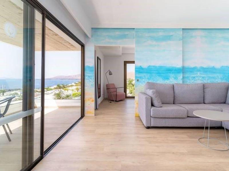 Soggiorno moderno con divano grigio, vetrata e vista mare dalla terrazza.