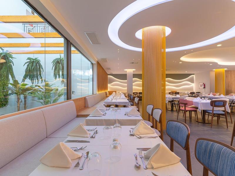 Ristorante elegante con interno moderno, grandi finestre e tavoli apparecchiati.