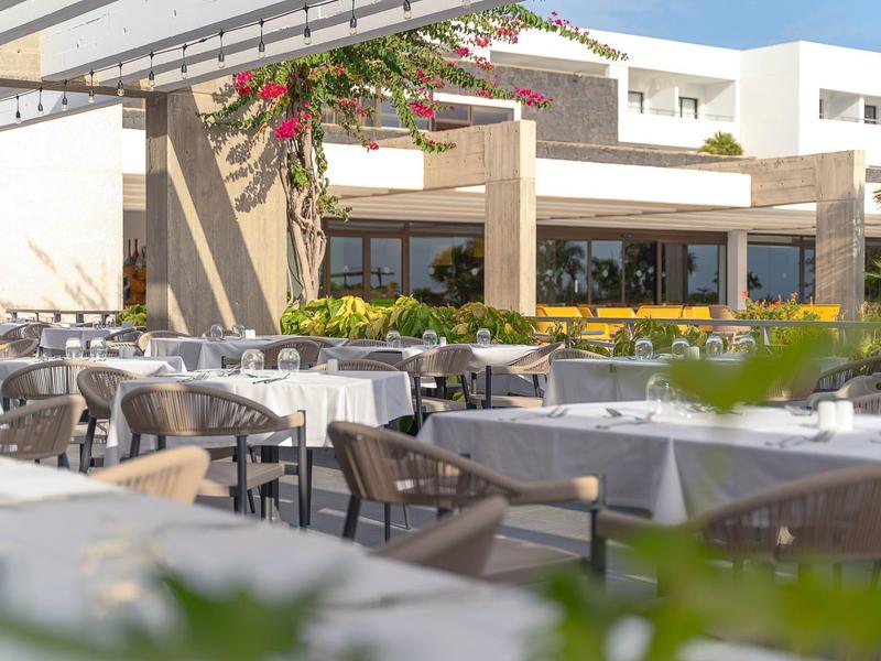 Ristorante all'aperto con tavoli apparecchiati e atmosfera moderna e luminosa.