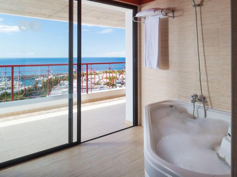 Bagno moderno con vasca da bagno che si affaccia su un balcone e vista sul mare.