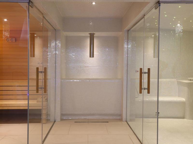 Espace bien-être moderne avec douches en verre et sauna en bois