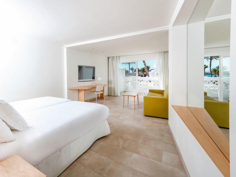 Chambre d'hôtel moderne avec lit double, télévision, bureau et petit coin salon avec canapé.