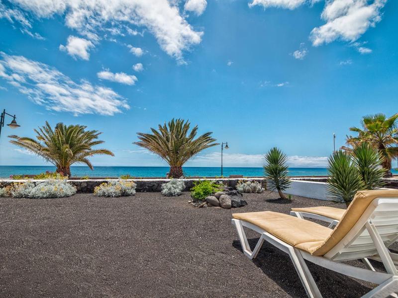 Sdraio rilassanti con vista sul mare e palme sotto un cielo azzurro.