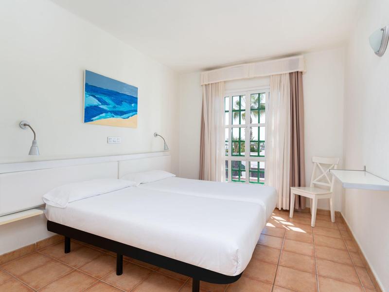 Camera luminosa arredata con letto matrimoniale, grande finestra e decorazioni minimali.