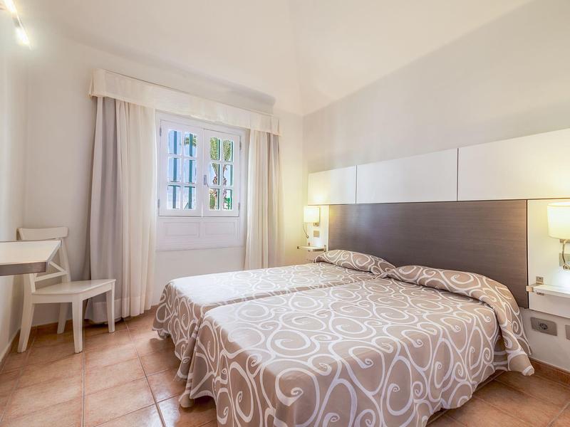 Camera d'hotel luminosamente arredata con letto matrimoniale, comodini e finestra con vista esterna.