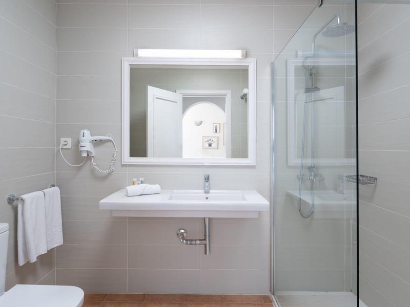 Bagno moderno con lavabo, specchio, portasciugamani e doccia in vetro.