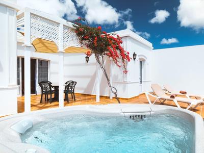 Jacuzzi na słonecznym tarasie obok białych budynków pod niebieskim niebem