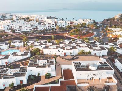 Aerial view of a holiday resort with white buildings and sea in the background.