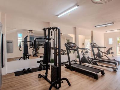 Modern gym with treadmills and strength training equipment, bright wooden floor and mirrored wall.