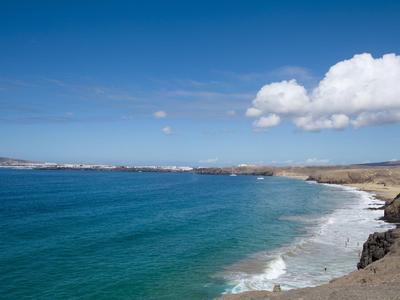 Plaża żwirowa z niebieską wodą i jałowym wybrzeżem pod niebieskim niebem.