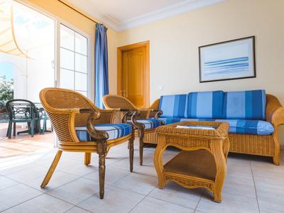 Przytulny kącik wypoczynkowy z wiklinowymi meblami i niebieską sofą obok otwartych drzwi na taras.