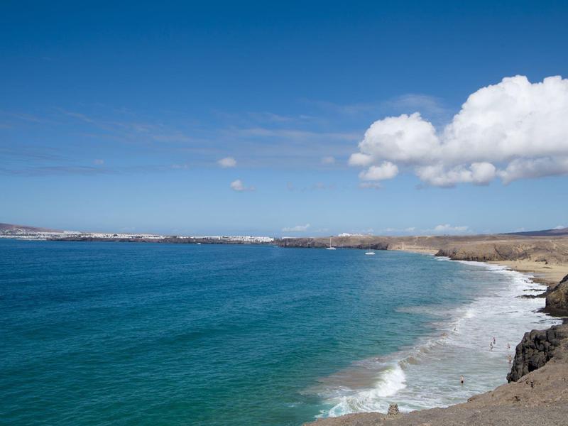 Plaża żwirowa z niebieską wodą i jałowym wybrzeżem pod niebieskim niebem.