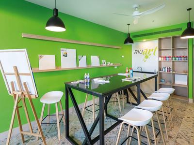 Moderne vergaderruimte met groene muur, hoge witte stoelen en een presentatiestandaard.