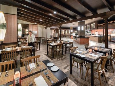 Ristorante spazioso con tavoli in legno, sedie confortevoli e atmosfera accogliente.