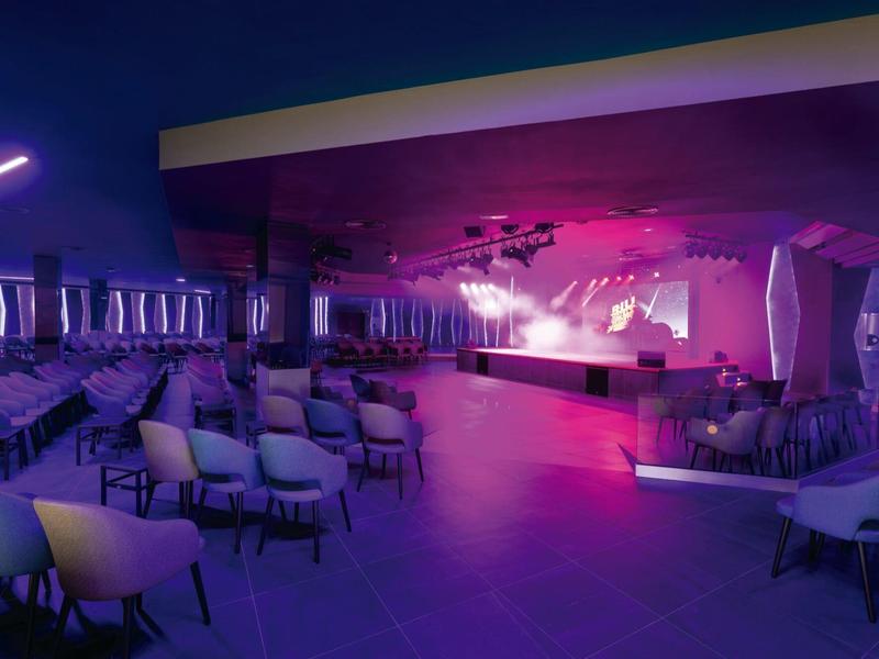 Sala eventi moderna con illuminazione del palco e molte sedie sotto luce viola