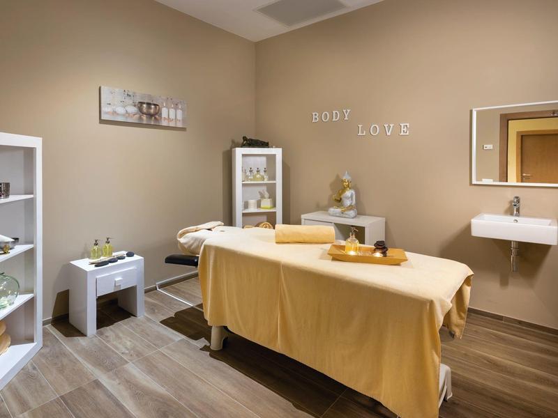 Stanza massaggi luminosa con lettino, decorazioni e atmosfera rilassante.