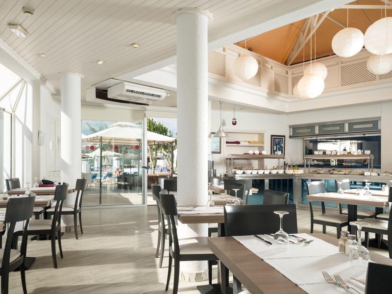 Ristorante dell'hotel luminoso e moderno con tavoli, sedie e grandi finestre.