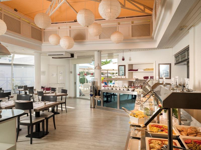 Sala da pranzo moderna con mobili in legno, lanterne di carta e buffet in una stanza luminosa.