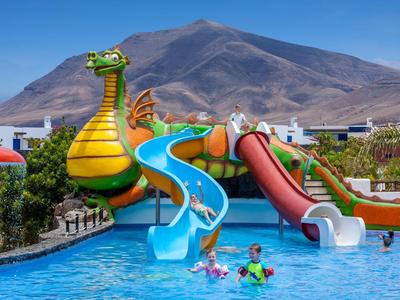 Parc aquatique avec toboggans dragons devant un décor montagneux par temps ensoleillé