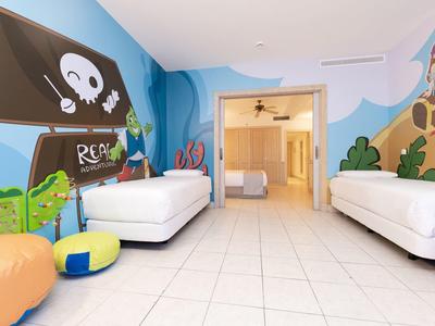 Chambre d'enfant avec motifs de pirates, deux lits simples et coussins colorés.