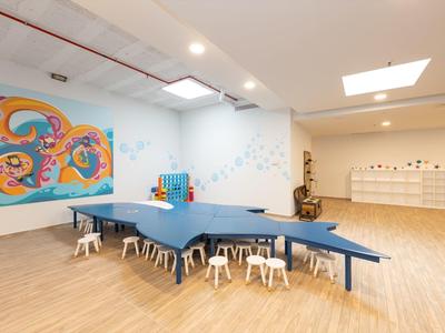 Salle de jeux lumineuse avec table de ping-pong, petits tabourets et peinture murale colorée.