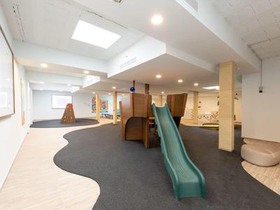 Espace de jeux intérieur moderne avec toboggan vert et sol en moquette dans un hôtel