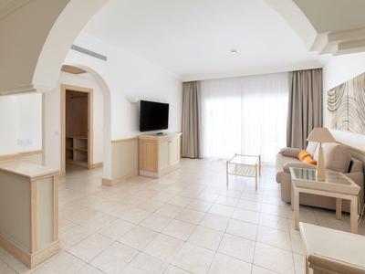 Salon moderne et lumineux avec canapé, télévision et grande fenêtre avec rideaux.