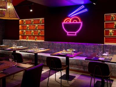 Restaurant moderne avec décoration en néon d'un bol avec des baguettes sur le mur.