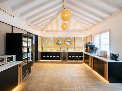 Salle de petit-déjeuner moderne avec armoires noires, parquet en bois et grandes fenêtres.