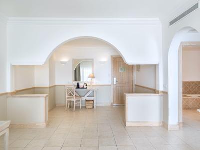 Hall d'hôtel lumineux avec arche blanche, chaise et table devant miroir