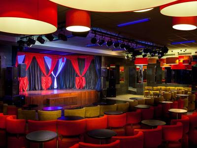 A theater room with red and yellow seating and a stage with red curtains.
