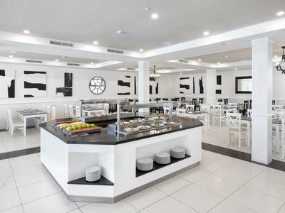 Cafétéria lumineuse et moderne avec buffet et tables et chaises blanches.