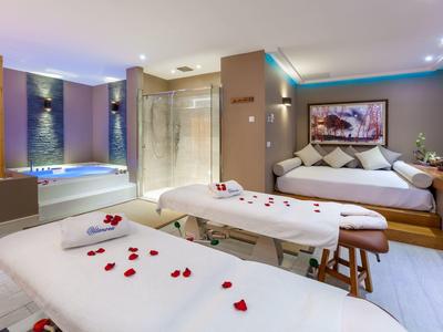 Salle de bien-être moderne avec deux tables de massage et des pétales de rose décoratifs.