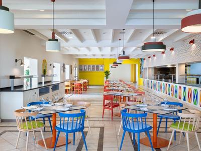 Intérieur de restaurant moderne et coloré avec des chaises bleues et rouges et des tables dressées.