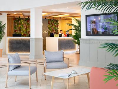Brightly furnished hotel lobby with seating area and reception in the background