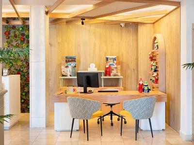 Modern hotel reception area with wooden wall and two chairs in front of the desk.