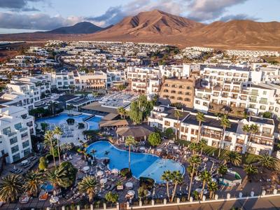 Large hotel resort with multiple pools, surrounded by mountains and serene landscape.